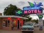 Ein klassisches Motiv des Blue Swallow Motels mit einem großen Schild und einem historischen grünen Auto davor.